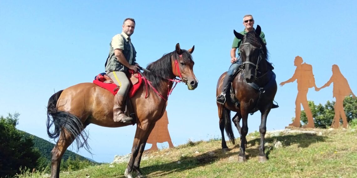 Due cavalieri in sella lungo la Via del Giovane in Calabria, accanto alle sagome che rappresentano i pellegrini del cammino