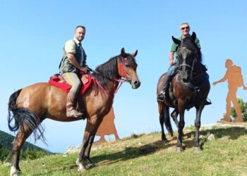 Due cavalieri in sella lungo la Via del Giovane in Calabria, accanto alle sagome che rappresentano i pellegrini del cammino