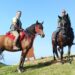 Due cavalieri in sella lungo la Via del Giovane in Calabria, accanto alle sagome che rappresentano i pellegrini del cammino